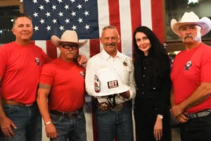 Group local firefighters posing with American flag backdrop.